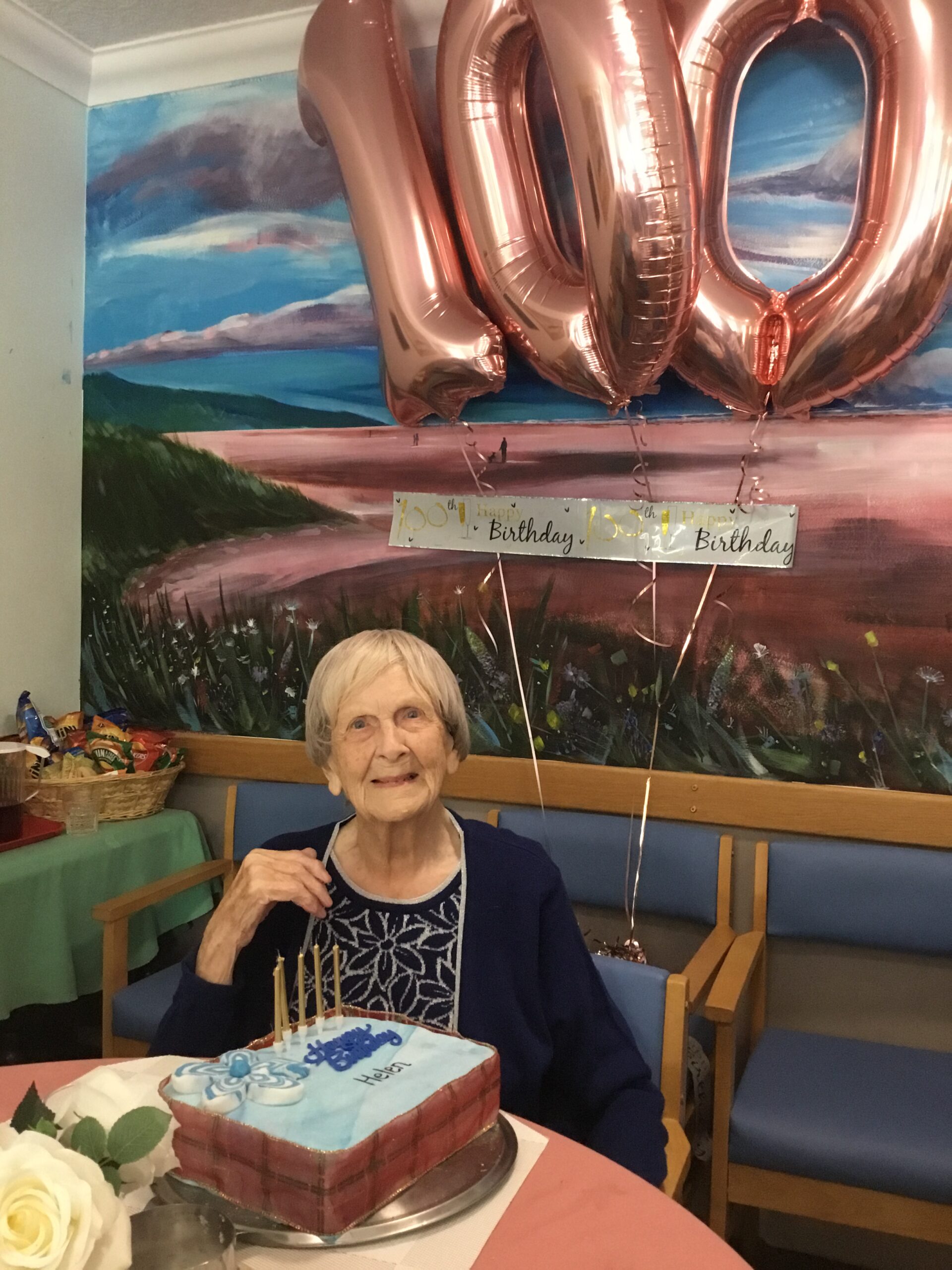 Helen with balloons and cake on her 100th birthday